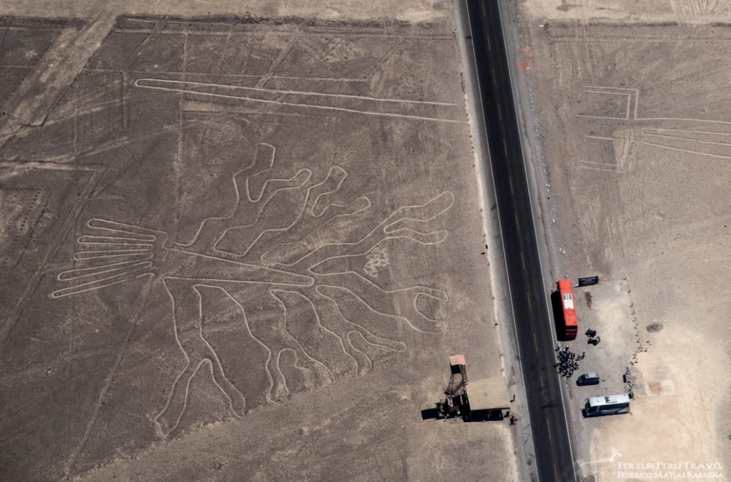 Nazca Lines - aerial photo of the Humming Bird geoglyph and the observation tower with a tour bus parked next to it.