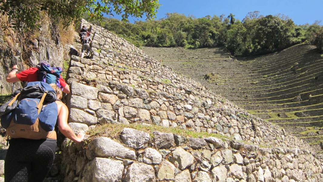 Inca trail hikers ascend the stone stairs at Wiñay Wayna on their way to Machu Picchu